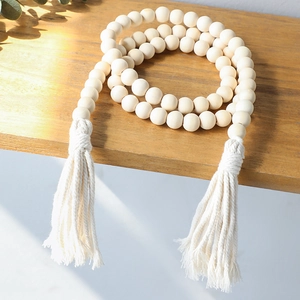 Close-up of bohemian wood bead curtain tieback with cotton tassels on a wooden surface
