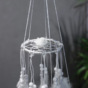 Detail of white dream catcher featuring handmade rose decor and hanging white feathers