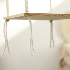 Macro view of knotted cotton rope and natural wood grain on boho hanging shelf