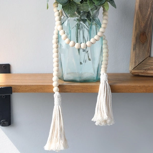 Bohemian wood bead curtain tieback with cotton tassels on a blue glass vase