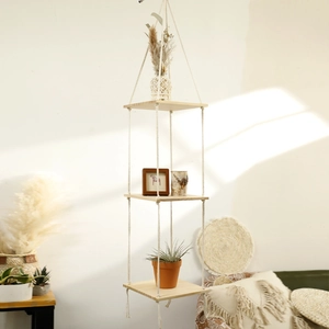 Three-tier macrame hanging shelf with natural wooden planks in a cozy living room scene
