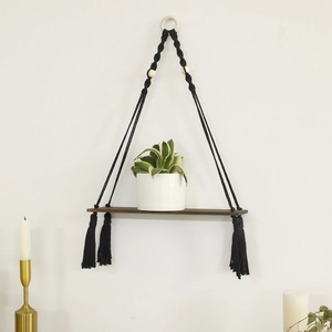 Detail of bohemian black cotton rope weaving and brown wooden wall shelf with tassels