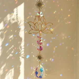 Gold metal lotus suncatcher with colorful crystal drop casting rainbow light on wall