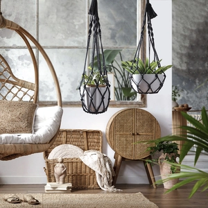Detail of black macrame plant hangers with handmade fringe in a boho home interior