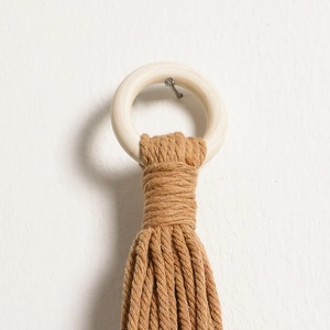 Detail of bohemian handmade cotton rope weaving around a natural wood ring hanger
