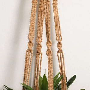 Close-up detail of hand-woven knots on a bohemian macrame plant hanger in natural jute rope