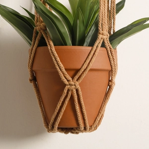 Detail of handcrafted macrame plant hanger with natural fiber texture and terracotta pot