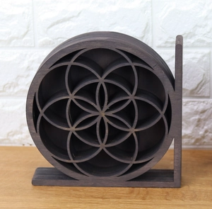 Detailed view of dark grey flower of life wooden geometric shelf on light wood desk