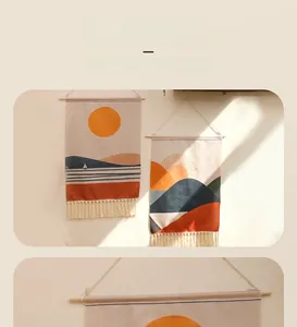 Dettaglio dell'arazzo boho tessuto con stampa di sole e montagne e frange color crema