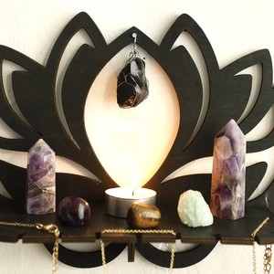 Close-up of black lotus wooden crystal display shelf with amethyst stones and candle