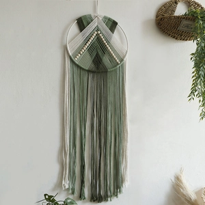 Detail of bohemian handmade woven wall hanging with wooden beads and green cotton tassels