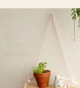 Detail of pink macrame shelf with wooden beads and bow for wall decor storage