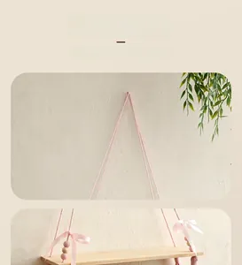 Detailed view of handmade wood floating shelf with pink tassels and decorative beads