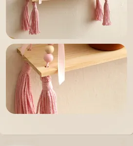 Close-up of handmade wood shelf featuring pink tassels and decorative wooden beads detail