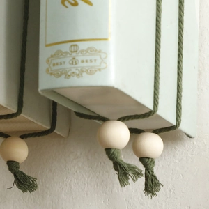 Detail of bohemian wall decor with green faux book, wooden beads and soft cotton tassels