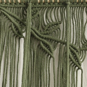 Close-up of handmade forest green macrame leaf design wall hanging on a wooden rod