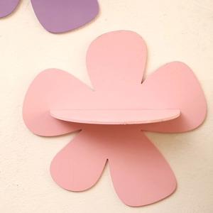 Close-up of pink flower-shaped wooden wall shelf with matte finish on white wall