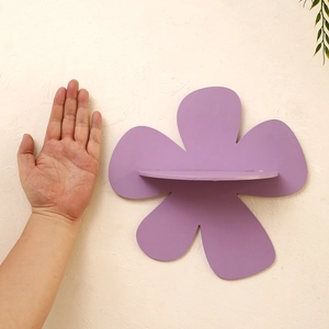 Detail of a purple flower-shaped wooden wall shelf with a sturdy horizontal ledge