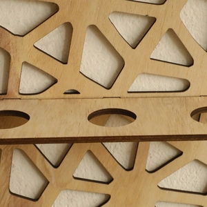 Detailed macro view of laser-cut geometric patterns and wood texture on a wall shelf