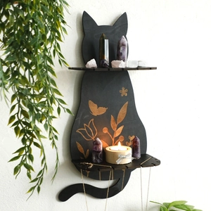 Detail of wooden cat crystal shelf with gold floral patterns on a white wall