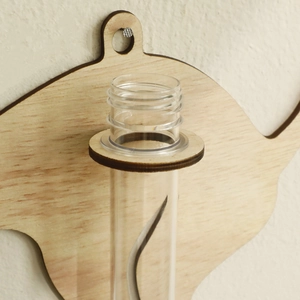 Macro detail of wooden teapot-shaped wall mount with a clear glass hydroponic test tube vase