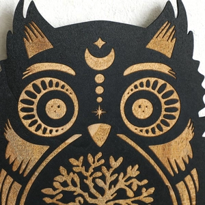 Macro shot of owl head carving details with mystical moon and star motifs on black wood