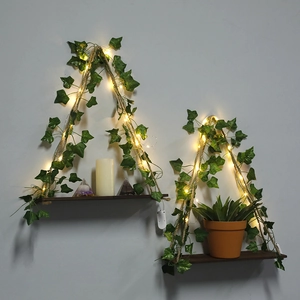 Detail view of boho hanging wood shelves with artificial ivy and glowing LED light strings