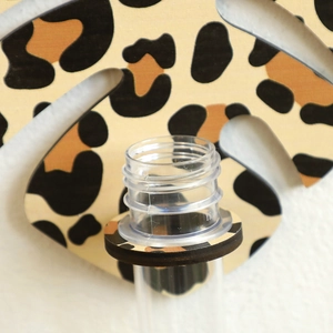 Detail view of leopard print leaf wall shelf showing the transparent vase holder structure