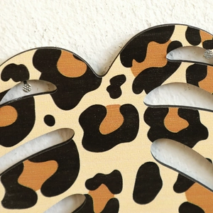 Macro detail of leopard print leaf-shaped wooden shelf with heart silhouette and hollow slots