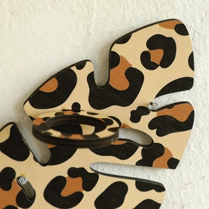 Detail view of leopard print leaf-shaped wooden wall shelf with circular ring holder