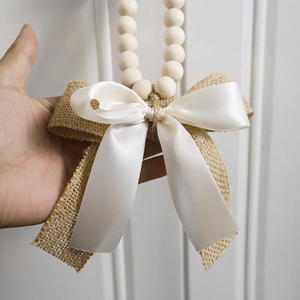 Detail of wooden beads garland with rustic burlap and satin ribbon bow for wall decoration