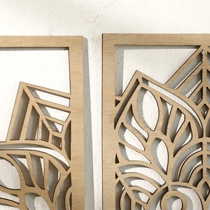 Detail of wooden leaf-shaped wall decor with intricate hollow patterns on a white wall