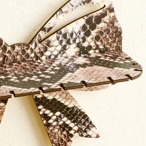 Detail view of the wooden snake print bow shelf featuring earring storage slots