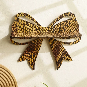 Detail of wooden bow-shaped jewelry wall shelf with snakeskin pattern for earring storage