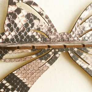 Macro detail of butterfly crystal shelf featuring wood texture and snakeskin pattern print
