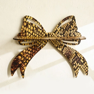 Detail of wooden bow-shaped wall shelf with yellow and black snakeskin pattern print