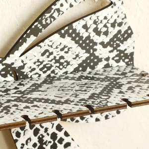 Detail of wooden display shelf with black and white snake print and earring hanging slots