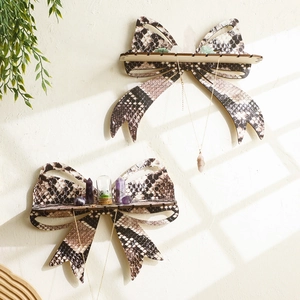 Set of two bow-shaped wooden crystal shelves with snakeskin print on a textured wall