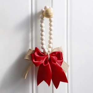 Detail of wooden bead garland with rustic burlap and red ribbon bow on white wall
