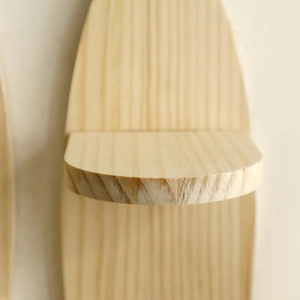 Close-up of oval wooden wall shelf showing natural pine grain and smooth curved edges