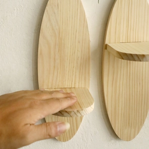 Minimalist oval surfboard shaped solid wood wall shelf with natural grain finish