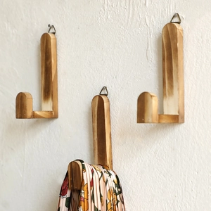 Detailed close-up of three L-shaped solid wood wall hooks with natural wood grain patterns