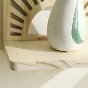 Detail of a fan-shaped wooden wall shelf featuring natural grain and hollowed-out patterns
