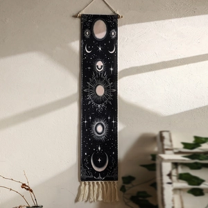 Detail of bohemian sun and moon tapestry with black celestial prints and beige fringe