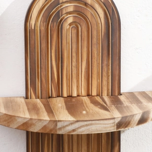 Close-up of charred wood wall shelf showing natural grain and arched groove texture