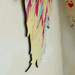 Detail view of colorful painted wooden wing wall decor with vibrant artistic patterns