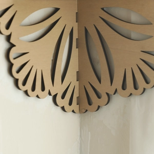 Detail view of the laser-cut hollow fan pattern on the wooden corner shelf joint