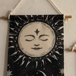Detail of bohemian sun and moon tapestry with hand-woven tassels on a wooden rod