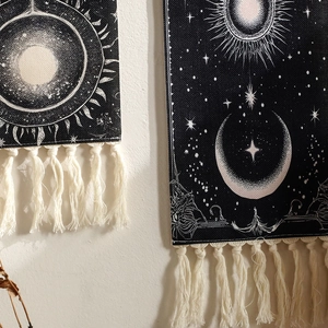 Detail of celestial sun and moon tapestry with handmade fringes on a textured wall