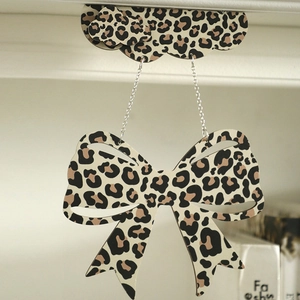 Close-up of leopard print bow pendant with cloud top and silver chain links